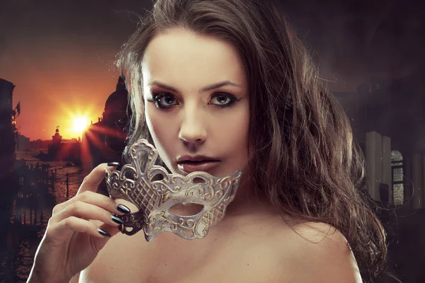 Beautiful brunette with Venetian mask. Young and beautiful woman on Venetian view background. — Stock Photo, Image