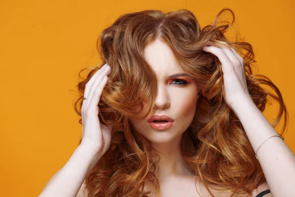Glückliche rothaarige junge Frau mit luxuriösen lockigen Haaren. Studioporträt auf gelbem Hintergrund. ausgezeichnetes Haar — Stockfoto