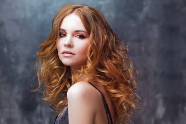 Mükemmel kıvırcık saçlı. Mutlu güzel kızıl saçlı kız. Stüdyo portre dokulu arka plan üzerinde.