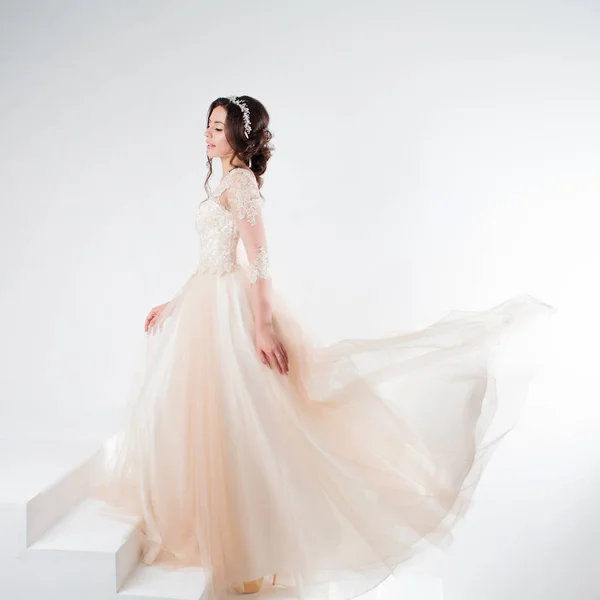 Portrait of a beautiful girl in a wedding dress. Bride in a luxurious dress standing on the stairs, climb up — Stock Photo, Image