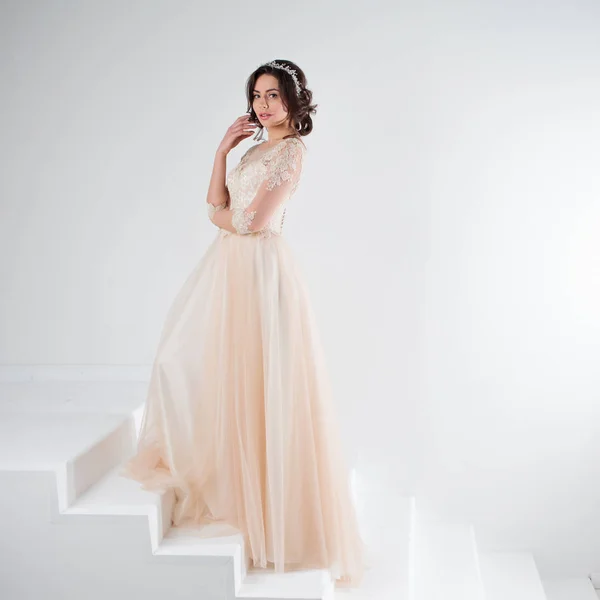 Portréja egy gyönyörű lány, egy esküvői ruha. Menyasszony egy fényűző ruhát, állva a lépcsőn felmászni — Stock Fotó
