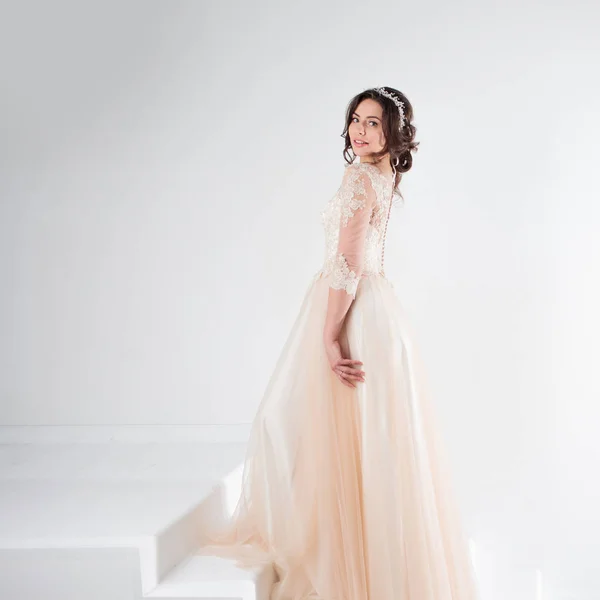 Portret van een mooi meisje in een trouwjurk. Bruid in een luxe jurk staande op de trap, klimmen — Stockfoto