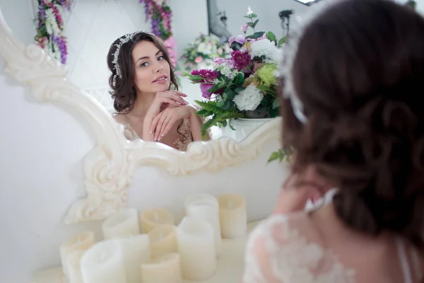 Pretty young woman in wedding dress. Sitting against the mirror. — Stock Photo, Image