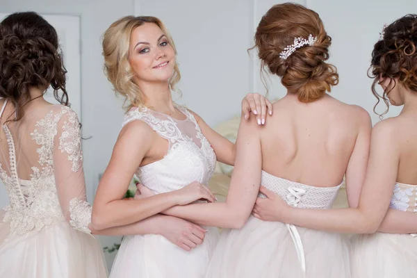 Bruid in bruiloft salon. Vier mooi meisje zijn in elkaars armen. Rug-, close-up lace rokken — Stockfoto
