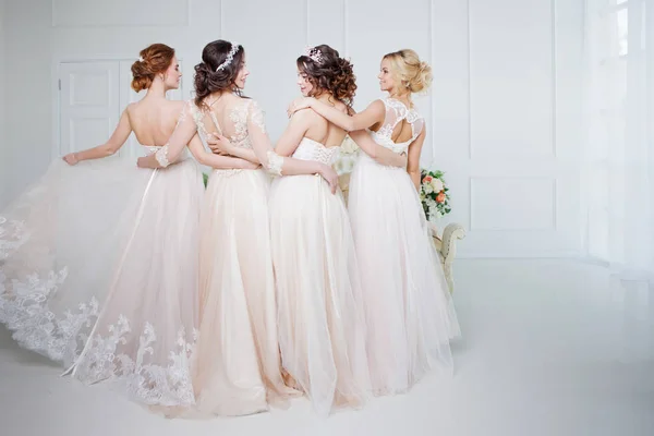 A menyasszony az esküvői szalon. Négy gyönyörű lány egymás karjaiban vannak. Hát, közeli csipke szoknya — Stock Fotó
