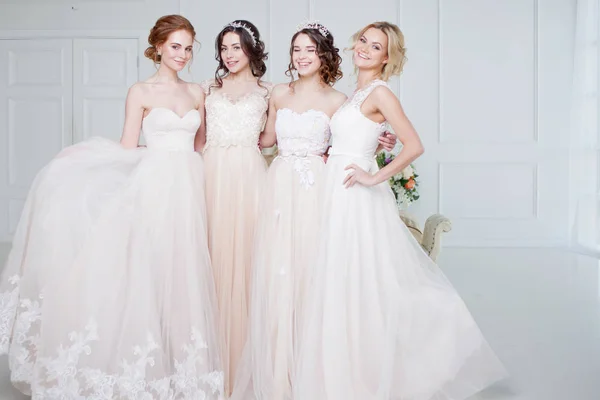 Невеста в свадебном салоне. Четыре красивые девушки в объятиях друг друга. Кружевные кружевные юбки — стоковое фото