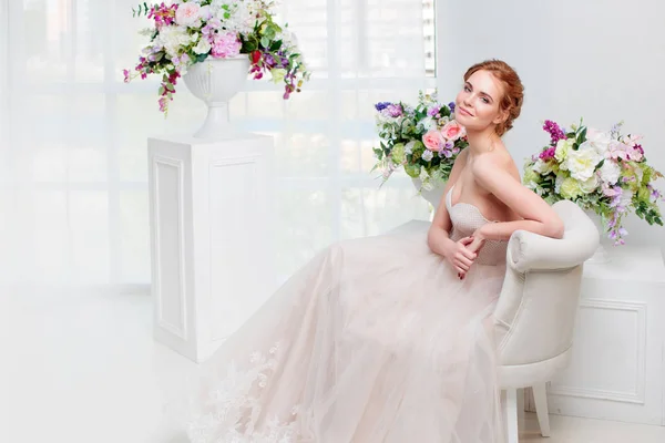 Portrait of a beautiful girl in a wedding dress. Bride in luxurious dress sitting on a chair — Stock Photo, Image