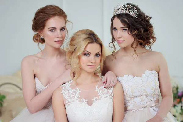 Three girls in wedding dresses. Beautiful delicate girls in the Bridal salon — Stock Photo, Image