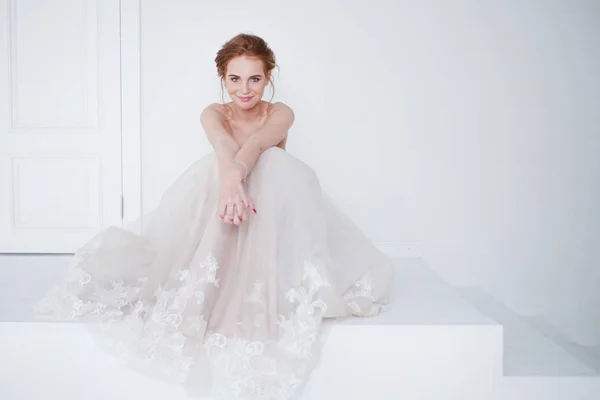 Retrato de uma menina bonita em um vestido de noiva. Noiva em vestido de luxo sentado no chão — Fotografia de Stock