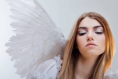Gökten bir melek. Beyaz kanatlı bir melek görüntüsündeki sarışın kız genç, harika. Portre yakın çekim