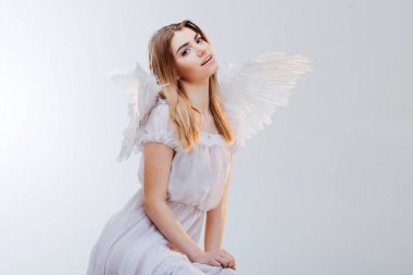 Gökten bir melek. Beyaz kanatlı bir melek görüntüsündeki sarışın kız genç, harika. Portre yakın çekim