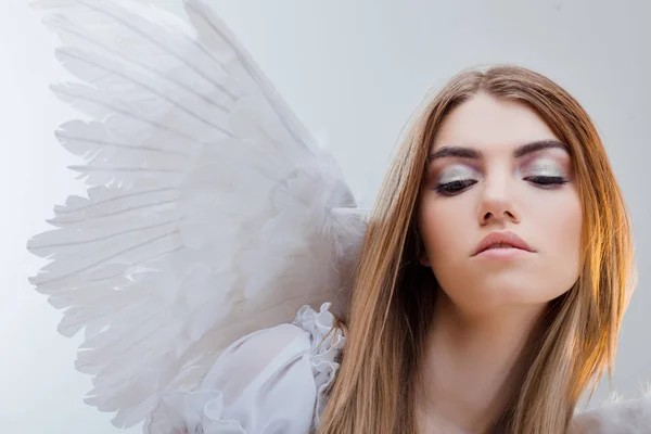 Um anjo do céu. Jovem, menina loira maravilhosa na imagem de um anjo com asas brancas. Retrato close-up — Fotografia de Stock