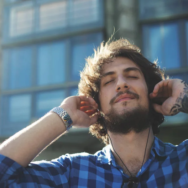 Szakállas fickó élvezi a zenét. Fiatal jóképű stílusos ember az utcán portréja. — Stock Fotó