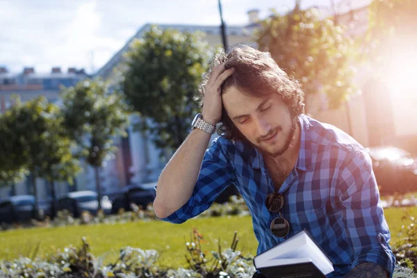 A fiatalember olvasókönyv a utcai, szabadban napsütéses napon — Stock Fotó