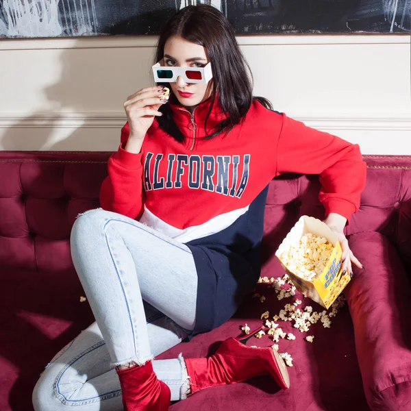 Молодая женщина в красной толстовке, смотрит фильмы дома, с попкорном . — стоковое фото
