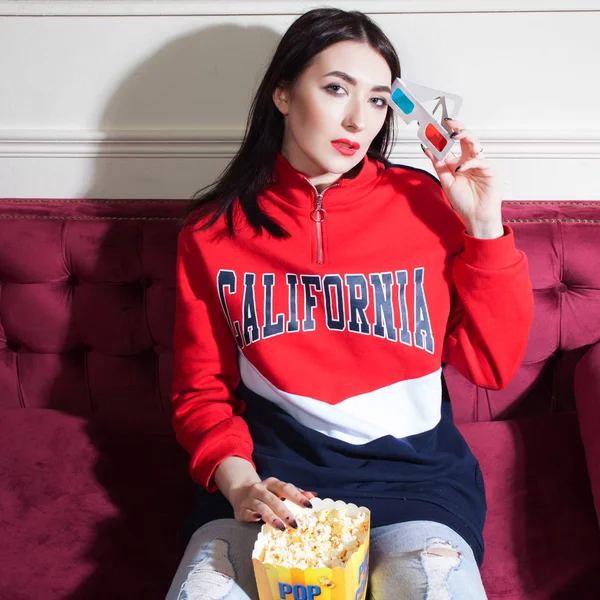 Junge Frau im roten Kapuzenpulli, zu Hause Filme guckt, mit Popcorn. — Stockfoto