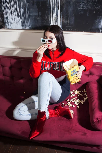 Mujer joven con capucha roja, viendo películas en casa, con palomitas de maíz . —  Fotos de Stock