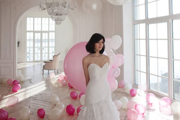 Young woman in wedding dress in luxury interior with a mass of pink and white balloons. — Stock Photo, Image
