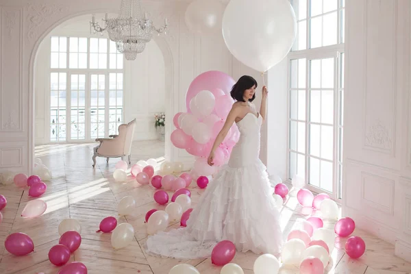 Mujer joven en vestido de novia en el interior de lujo con una masa de globos de color rosa y blanco . —  Fotos de Stock