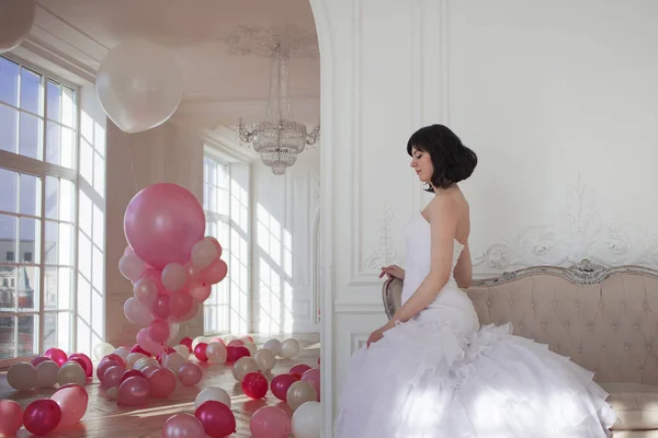 Young woman in wedding dress in luxury interior with a mass of pink and white balloons. — Stock Photo, Image