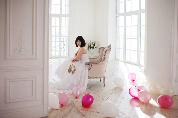 분홍색과 흰색 풍선의 질량을 가진 럭셔리 인테리어에서 웨딩 드레스에서 젊은 여자. — 스톡 사진
