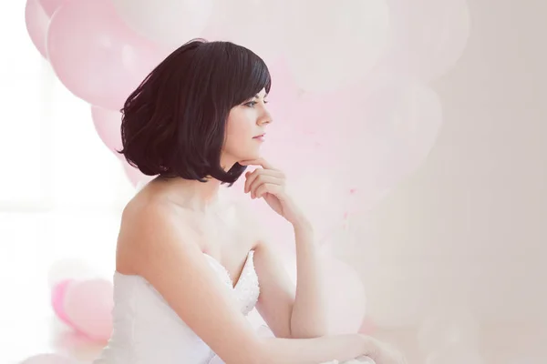 Mujer joven en vestido de novia en el interior de lujo con una masa de globos de color rosa y blanco . — Foto de Stock