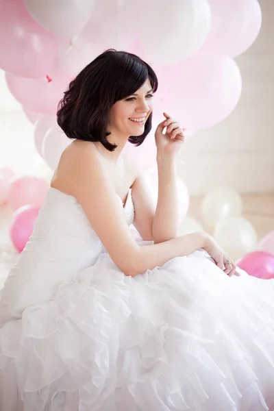 Mujer joven en vestido de novia en el interior de lujo con una masa de globos de color rosa y blanco . — Foto de Stock