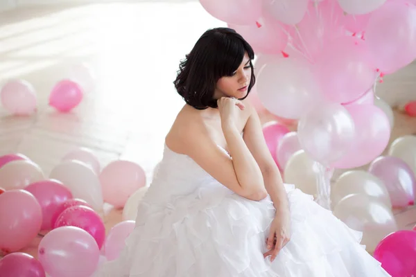 Mujer joven en vestido de novia en el interior de lujo con una masa de globos de color rosa y blanco . — Foto de Stock