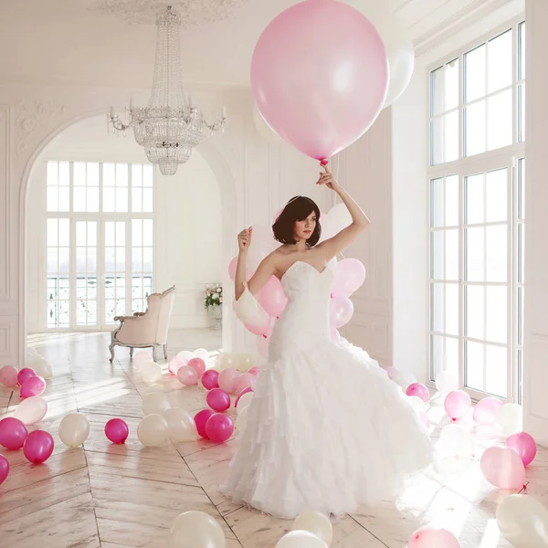 Mujer joven en vestido de novia en el interior de lujo con una masa de globos de color rosa y blanco . —  Fotos de Stock