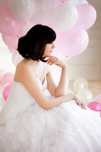 Mujer joven en vestido de novia en el interior de lujo con una masa de globos de color rosa y blanco . — Foto de Stock