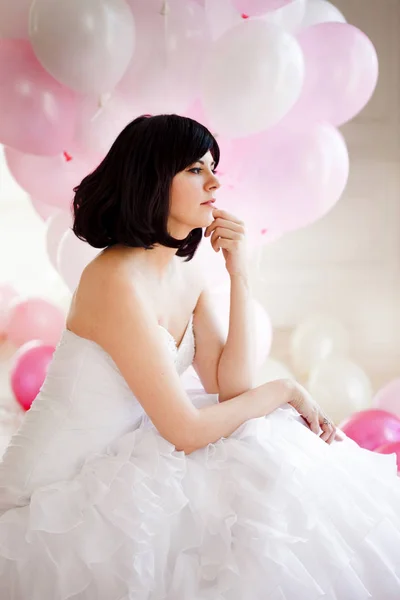 Mujer joven en vestido de novia en el interior de lujo con una masa de globos de color rosa y blanco . — Foto de Stock