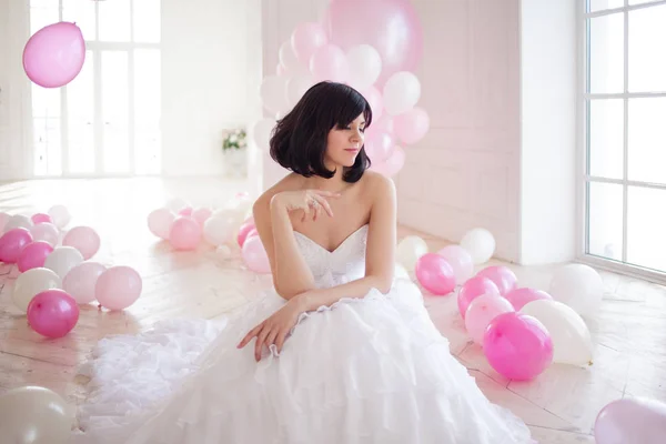 Mujer joven en vestido de novia en el interior de lujo con una masa de globos de color rosa y blanco . —  Fotos de Stock