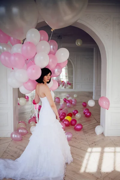 Young woman in wedding dress in luxury interior with a mass of pink and white balloons. — Stock Photo, Image