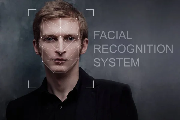 Systém rozpoznávání obličeje, koncept. Mladý muž na šedém pozadí, rozpoznávání obličeje — Stock fotografie
