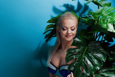 Güzel ve çekici sarışın kız palmiye ağaçları ve tropik bitkiler arasında. Mutluluk, denizin üzerinde kalan