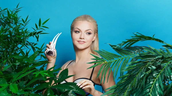 Hermosa y encantadora chica rubia con gafas de sol entre palmeras y plantas tropicales . —  Fotos de Stock