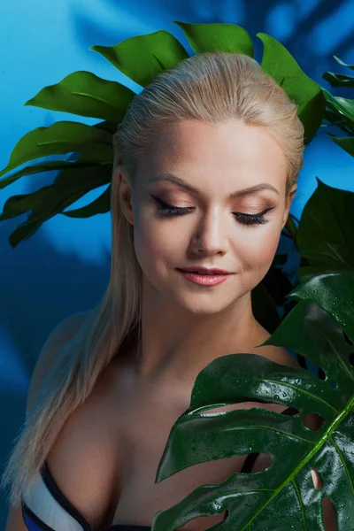Jonge vrouw in blauwe bikini op blauwe achtergrond. — Stockfoto