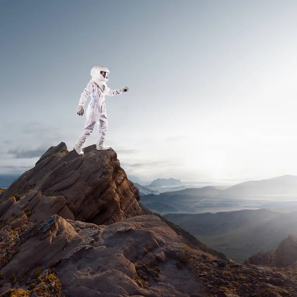 Retrato de astronauta con traje espacial. Astronauta futurista en el planeta, de pie en la cima de una montaña y extiende su mano — Foto de Stock