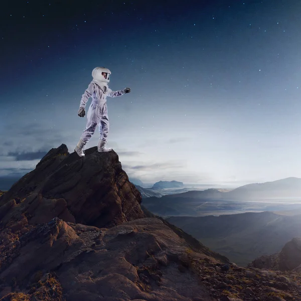 Retrato de astronauta num fato espacial. Astronauta futurista no planeta, em pé no topo de uma montanha e estende a mão — Fotografia de Stock