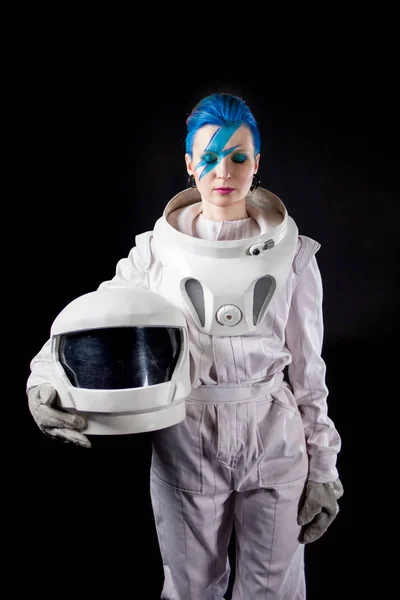 Astronauta sobre um fundo preto, uma jovem com arte facial no traje espacial. Capacete nas mãos — Fotografia de Stock