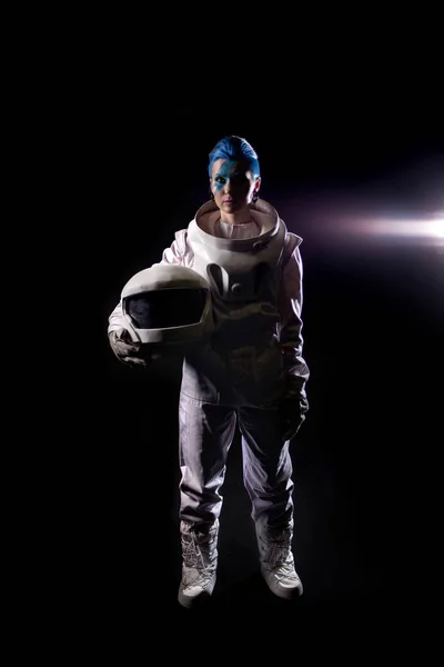 Astronauta sobre un fondo negro, una joven con cara de arte en el traje espacial. Casco en las manos —  Fotos de Stock