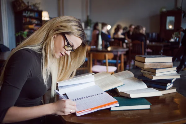 Blond flicka i biblioteket, gör en sammanfattning av läroböcker. Utbildning, förberedning inför examen — Stockfoto