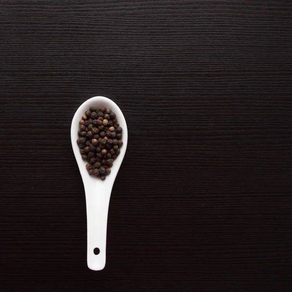 Condimento en cuchara blanca sobre mesa negra. Cocinar. espacio de copia —  Fotos de Stock