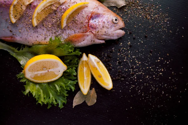 Färsk öring och ingredienser att förbereda fisk rätter på svart bord — Stockfoto