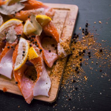 Dilimlenmiş somon biftek limon ve baharatlar ile. Ahşap bir gemide.