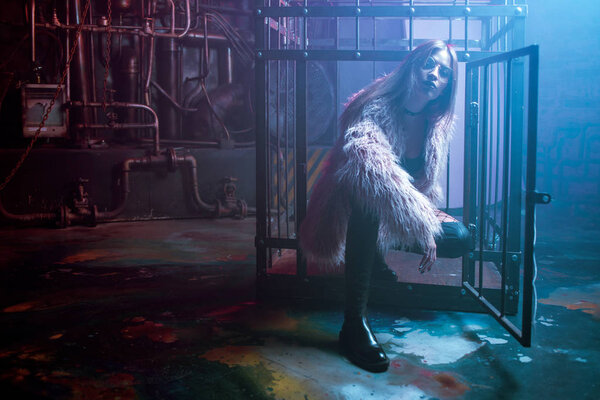 Молодая привлекательная женщина со стильной одеждой. Красивая девушка в пушистом розовом шубе, на фоне киберпанка. Неоновый свет
