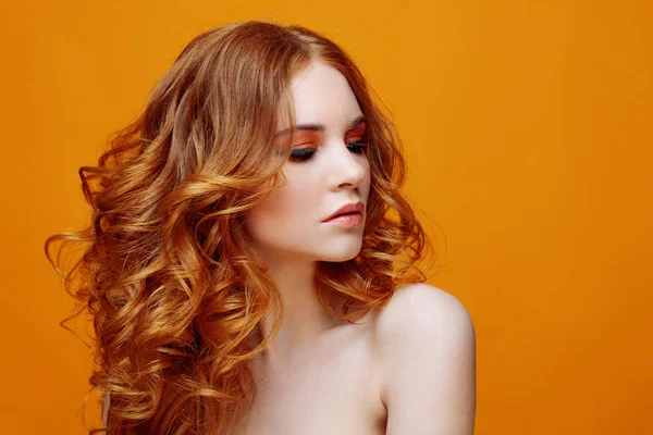 Красивая рыжая девушка с роскошными вьющимися волосами. Студийный портрет на желтом фоне. Отличная прическа — стоковое фото