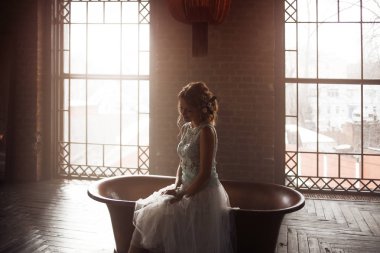 Dantel elbise genç kadın ve saçlarını gülümseyen çiçeklerle süslenmiş oturur ışığa karşı.