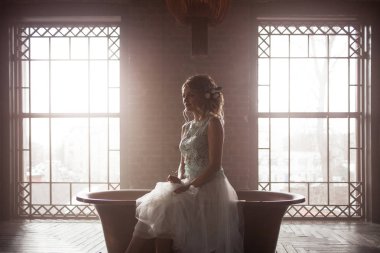 Dantel elbise genç kadın ve saçlarını gülümseyen çiçeklerle süslenmiş oturur ışığa karşı.