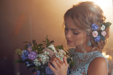 Buket çiçek ile gelinlik içinde genç güzel kadın. Düğün saç modeli, saç çiçekleri.